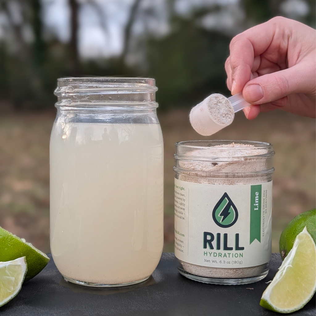 Hand scooping Rill Hydration electrolyte drink mix (lime) out of the jar. 
