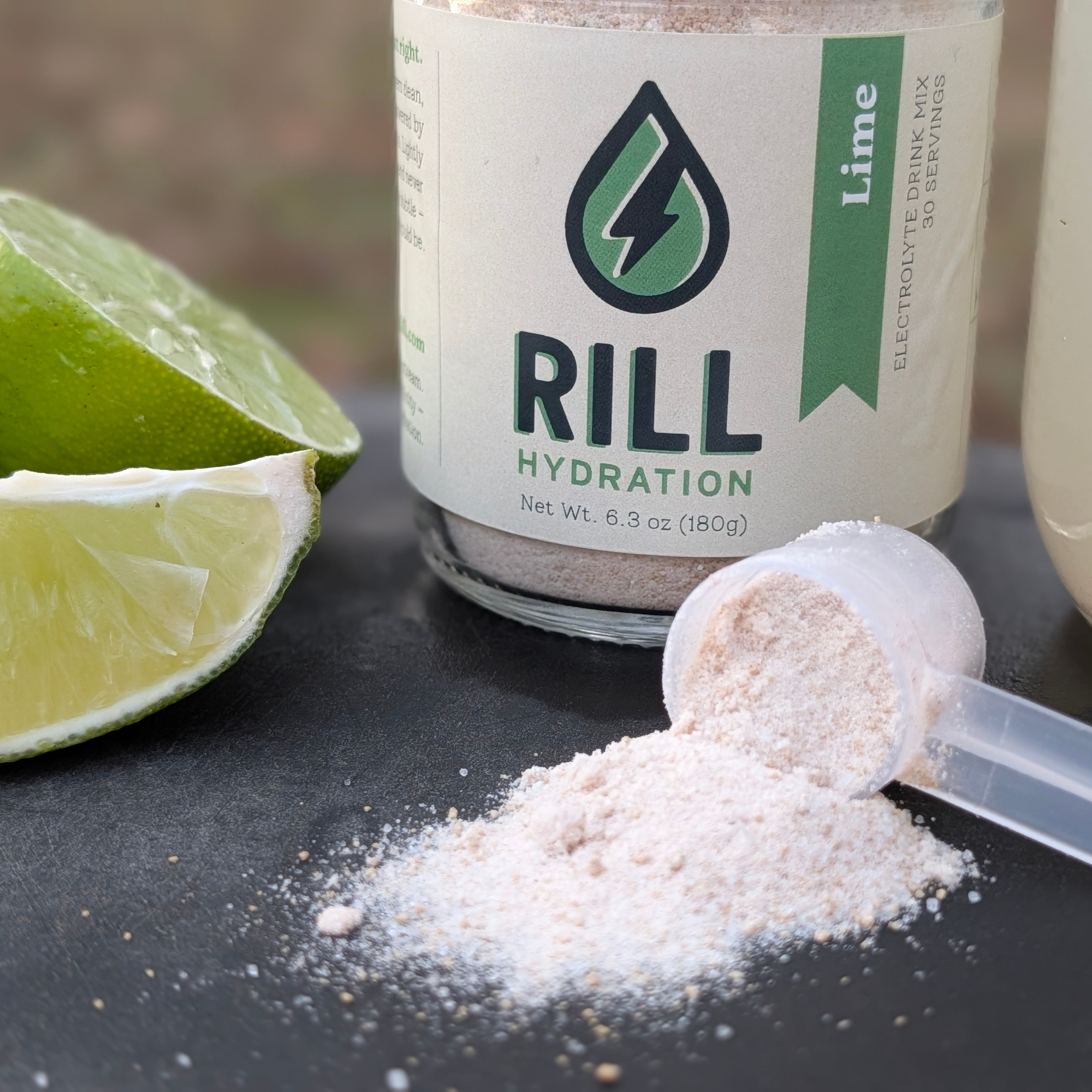 RILL Hydration Electrolyte drink mix powder with lime slices on a dark surface